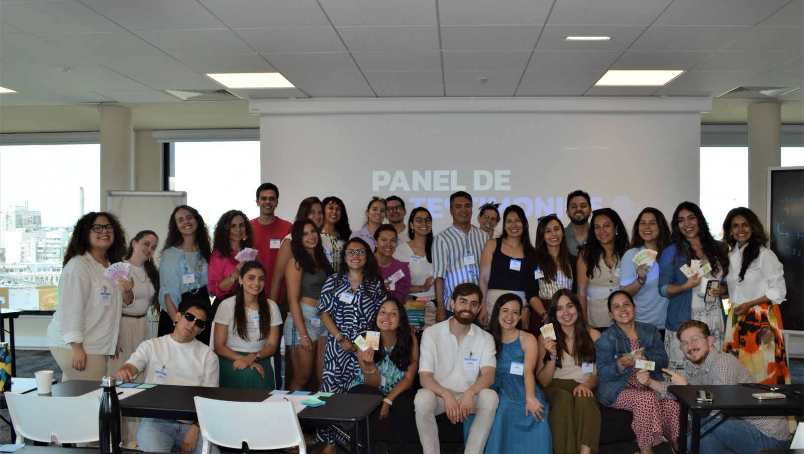 Foto de grupo de la comunidad IMT en el Summit 2025, frente al panel de testimonios