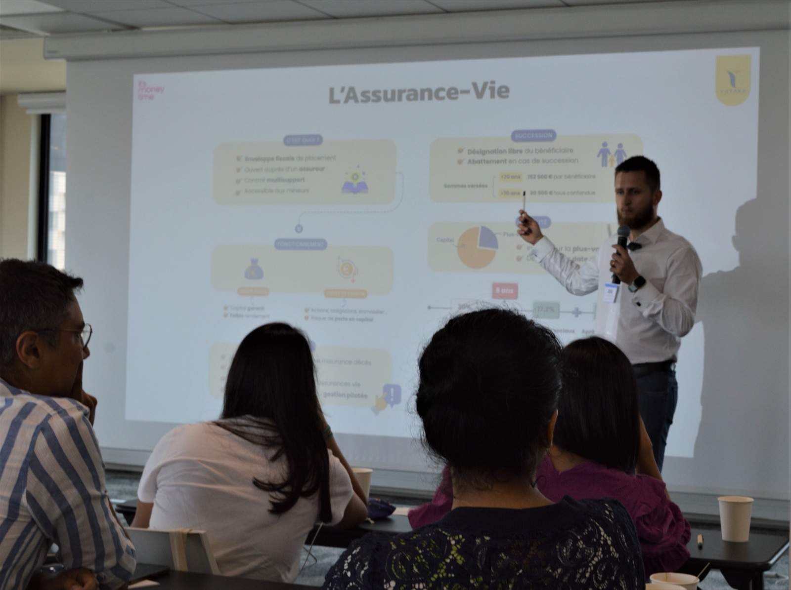 Chris explicando la assurance-vie frente a la pantalla